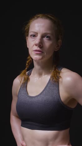 Vertical-Video-Studio-Portrait-Of-Mature-Woman-Wearing-Gym-Fitness-Clothing-Sweating-Recovering-After-Exercise